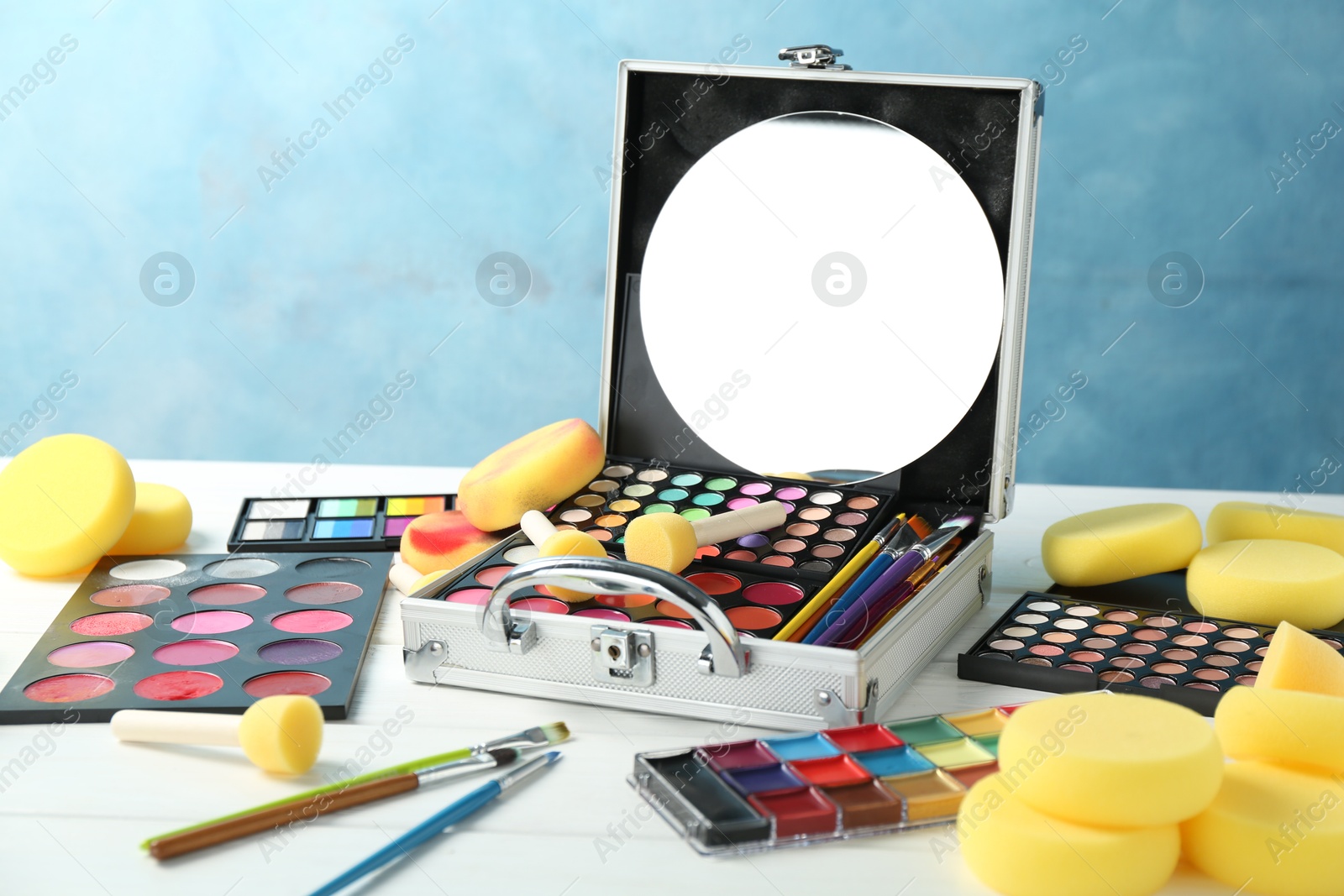 Photo of Face paints, tools and makeup products on white wooden table