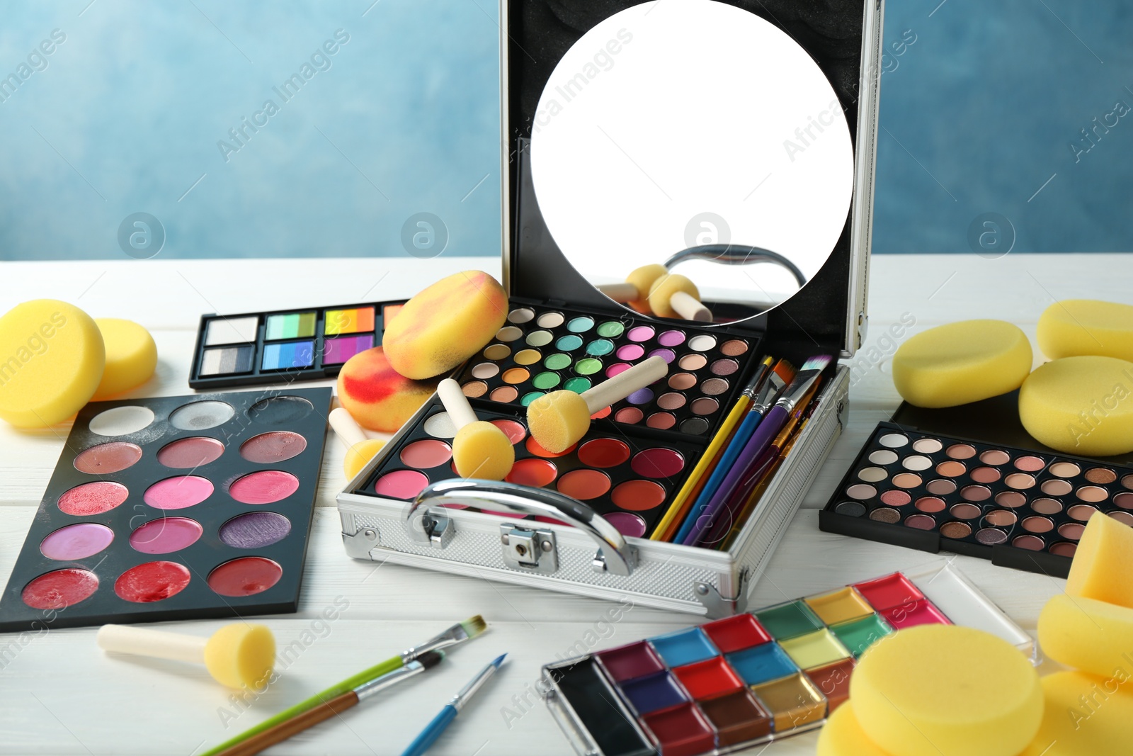 Photo of Face paints, tools and makeup products on white wooden table