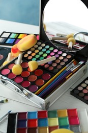 Photo of Face paints, tools and makeup products on white wooden table, closeup