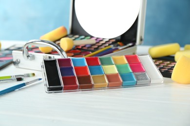 Photo of Face paints and tools on white wooden background