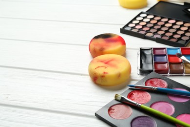 Photo of Face paints, tools and makeup products on white wooden background, closeup. Space for text