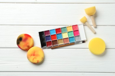 Photo of Face paints and tools on white wooden background, flat lay