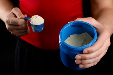 Photo of Sportsman taking protein with scoop on dark background, closeup