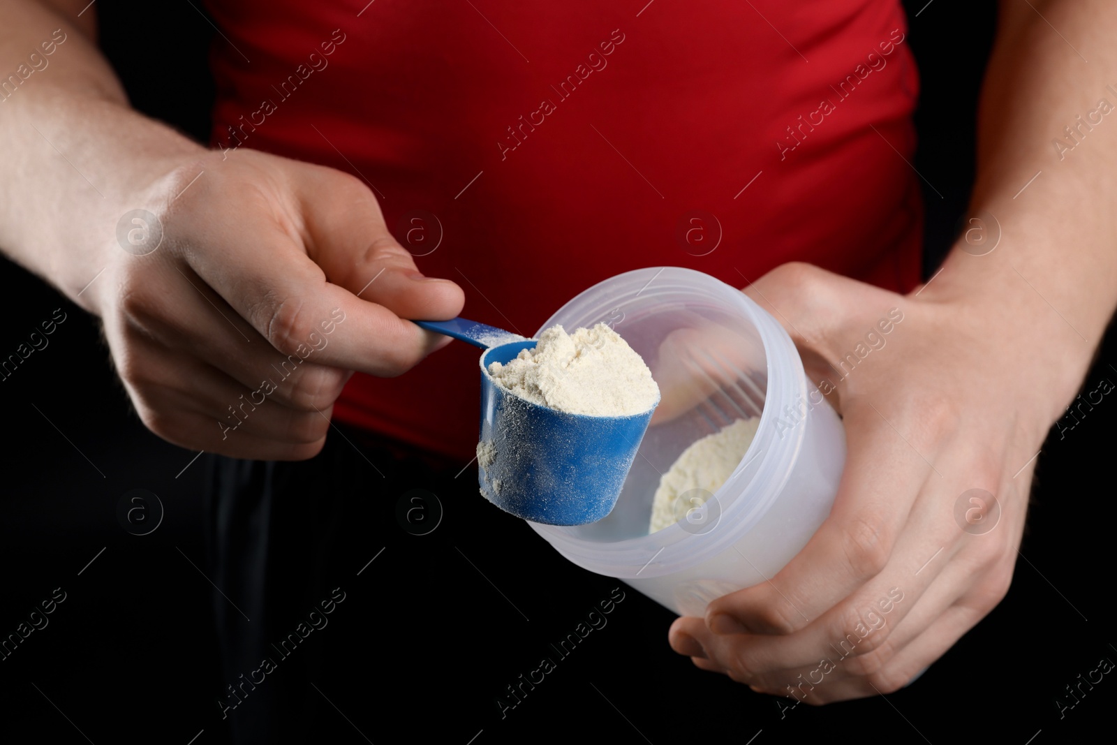 Photo of Sportsman adding protein into shaker on dark background, closeup