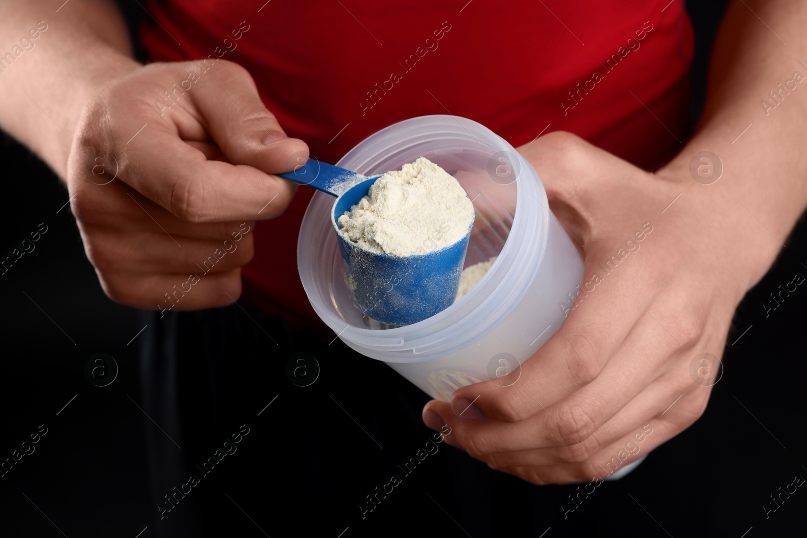 Photo of Sportsman adding protein into shaker on dark background, closeup