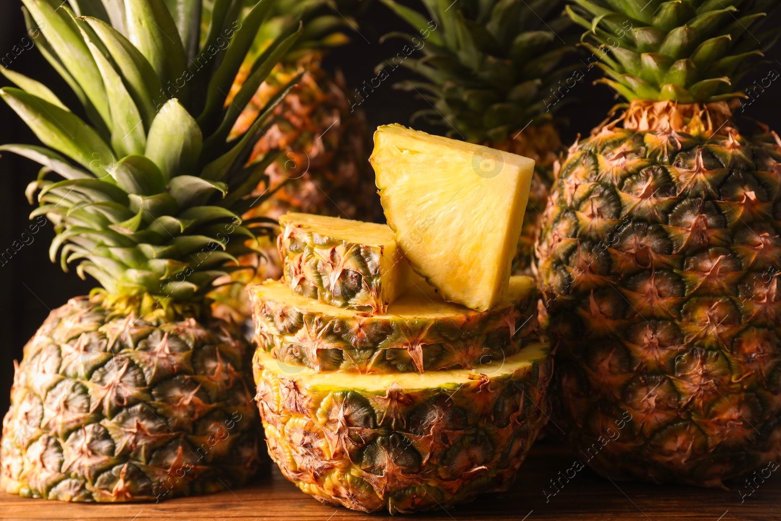 Photo of Whole and cut ripe pineapples on wooden table