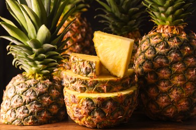 Photo of Whole and cut ripe pineapples on wooden table