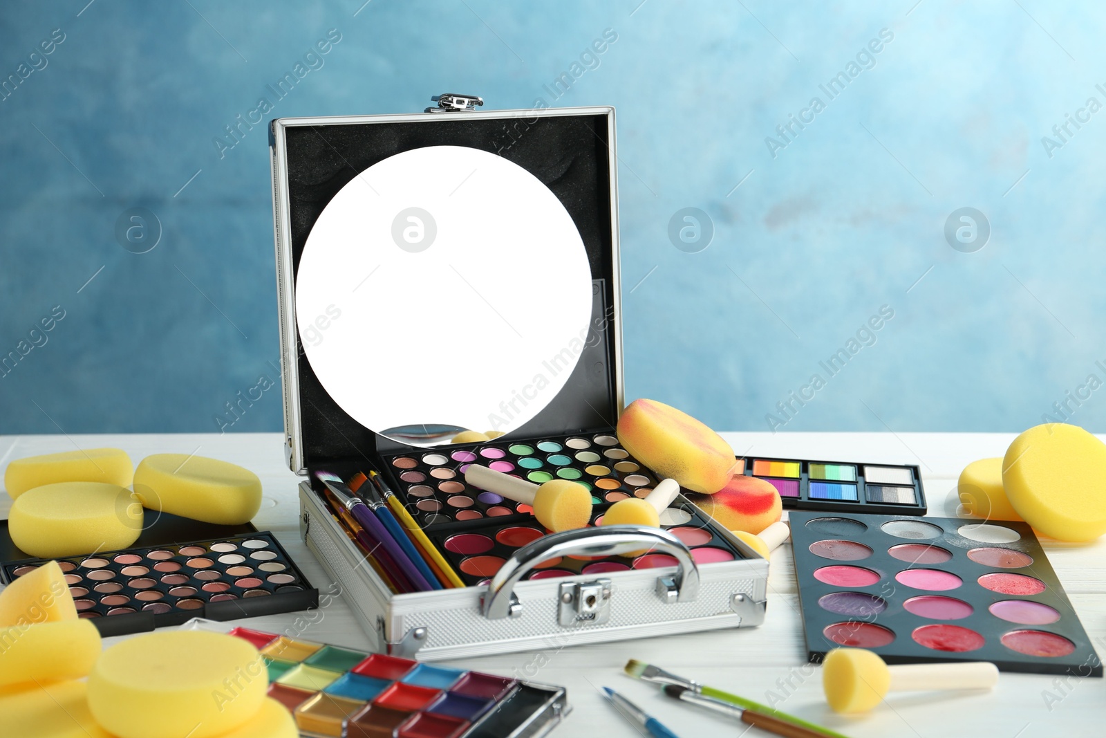 Photo of Face paints, tools and makeup products on white wooden table