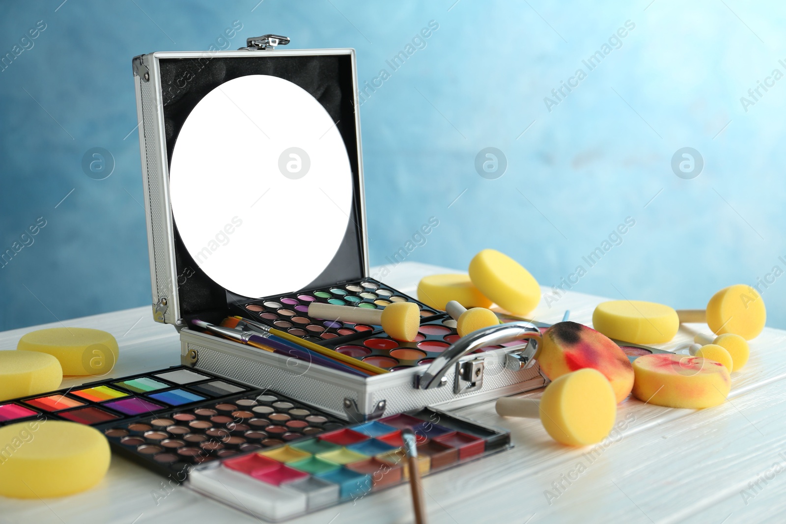 Photo of Face paints, tools and makeup products on white wooden table