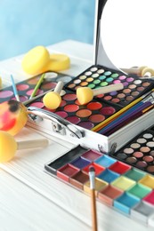 Photo of Face paints, tools and makeup products on white wooden background, closeup