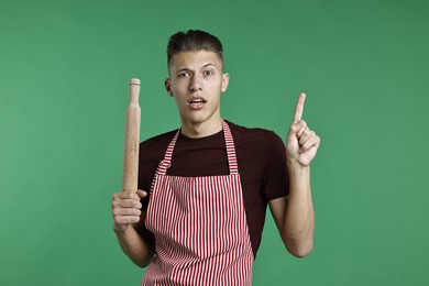 Photo of Man with rolling pin pointing at something on green background