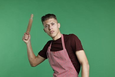 Photo of Angry man with rolling pin on green background