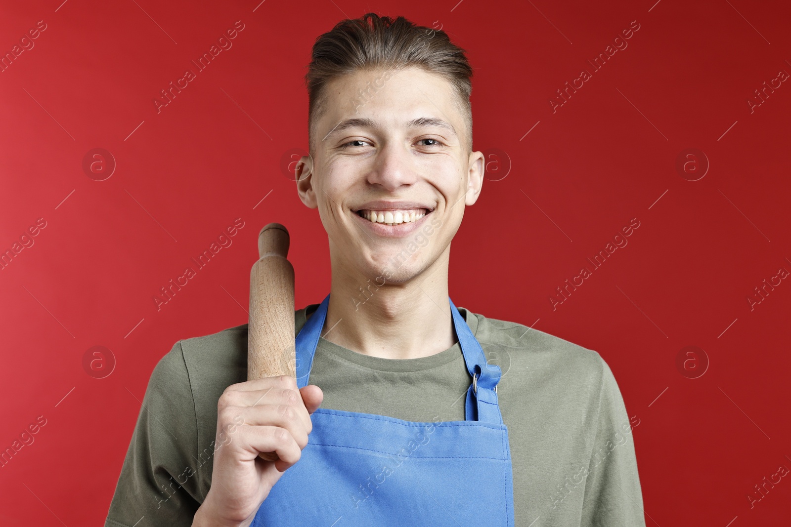 Photo of Happy man with rolling pin on red background