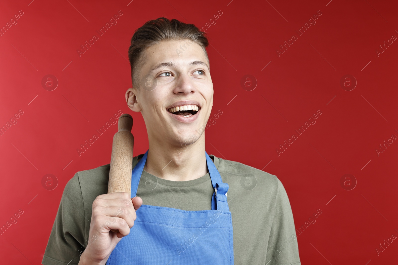 Photo of Happy man with rolling pin on red background