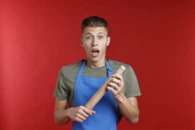 Photo of Emotional man with rolling pin on red background