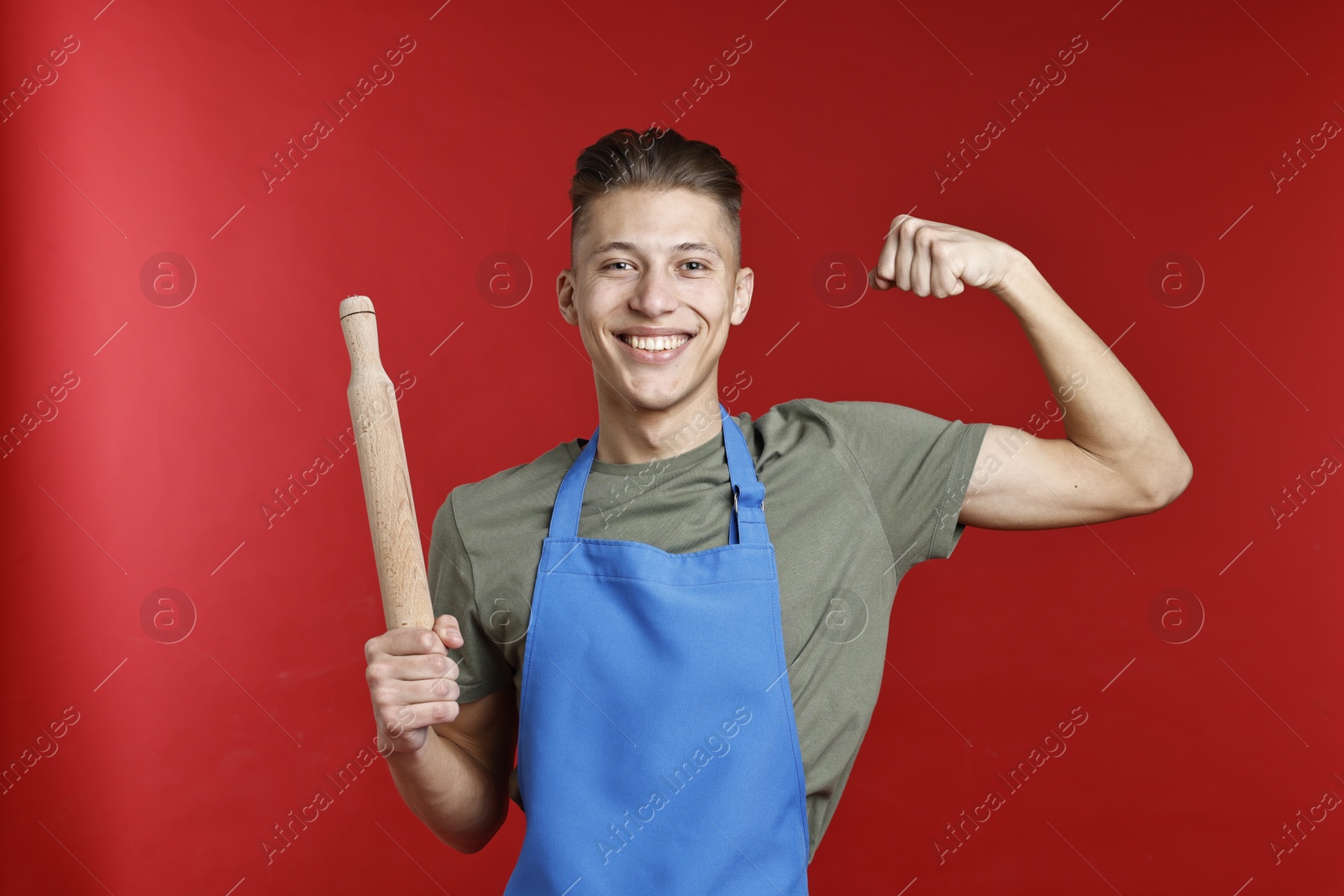 Photo of Happy man with rolling pin showing strength on red background