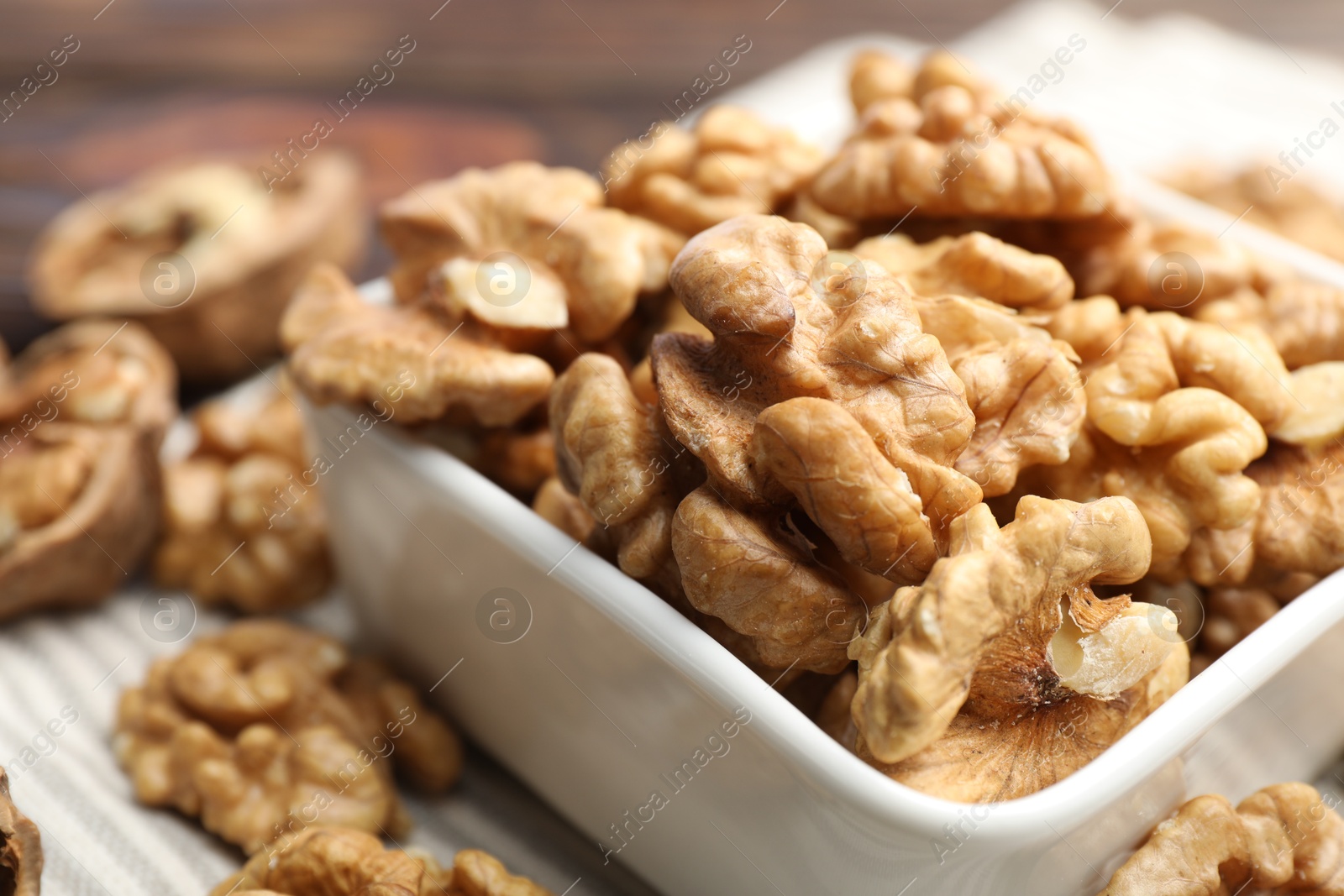 Photo of Peeled walnuts in bowl on table, closeup