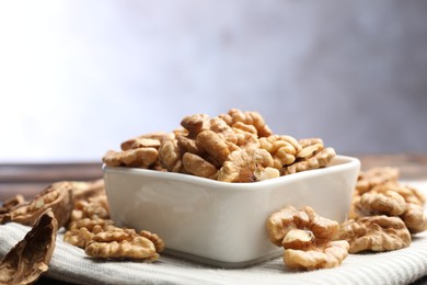 Photo of Peeled walnuts in bowl on table against light background, closeup