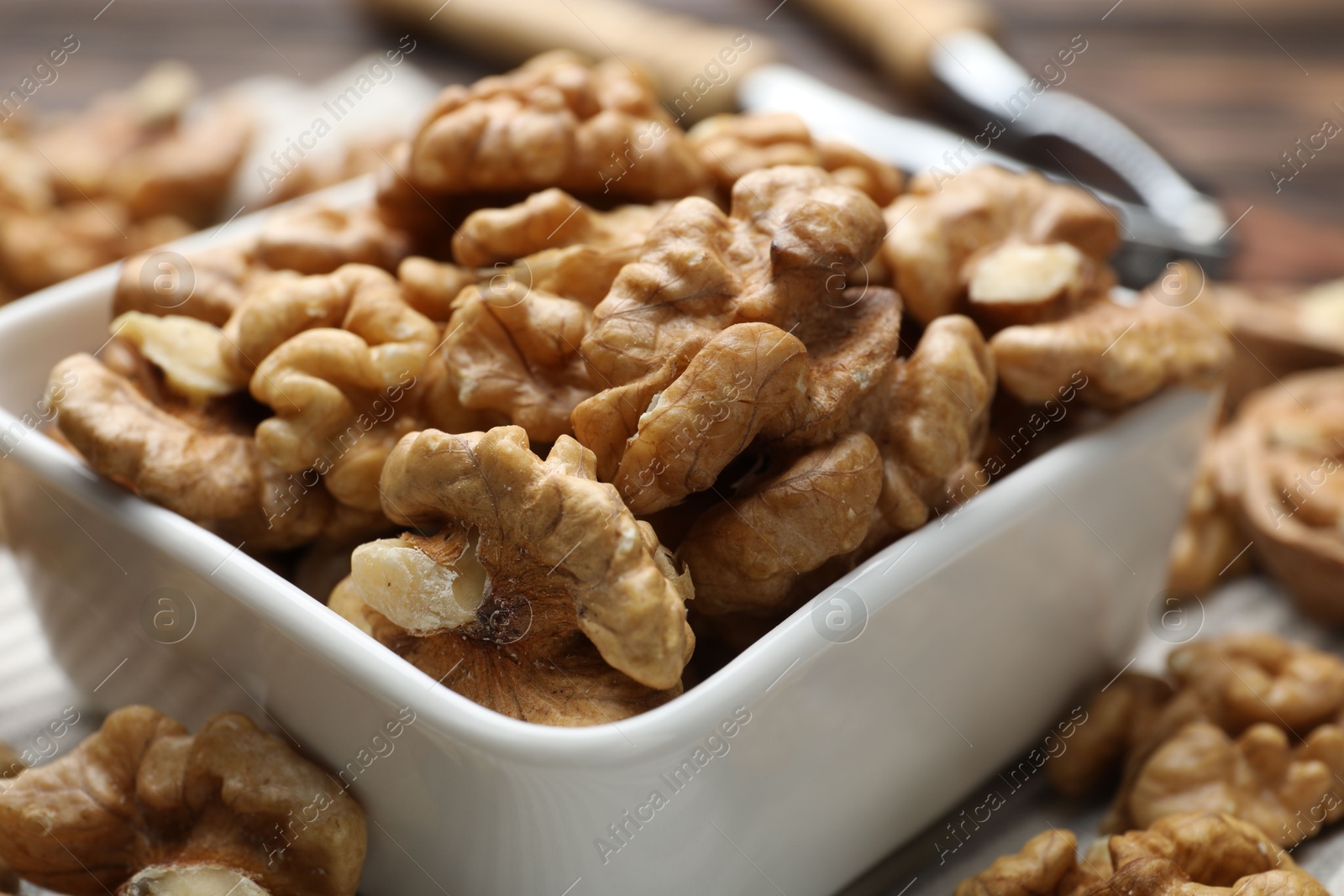 Photo of Peeled walnuts in bowl on table, closeup