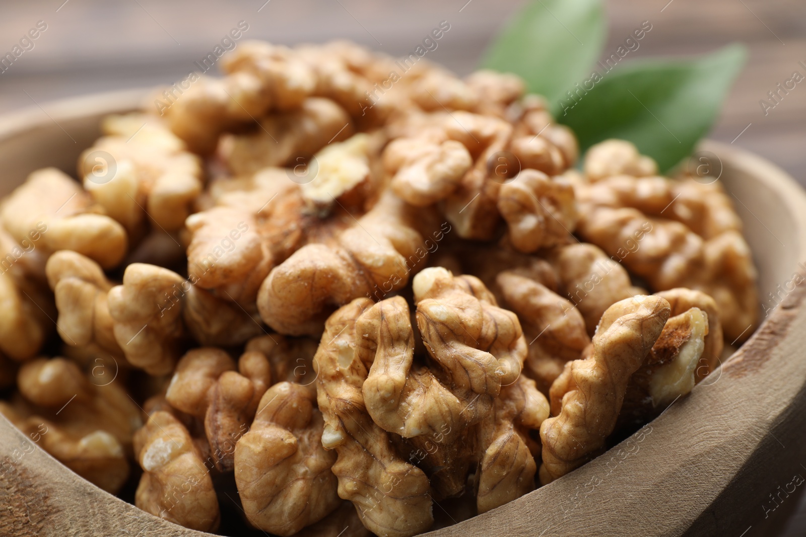 Photo of Peeled walnuts in bowl on table, closeup