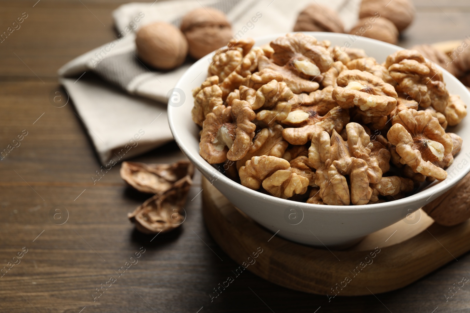 Photo of Peeled walnuts in bowl on wooden table, closeup. Space for text