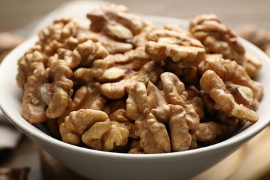 Photo of Peeled walnuts in bowl on table, closeup