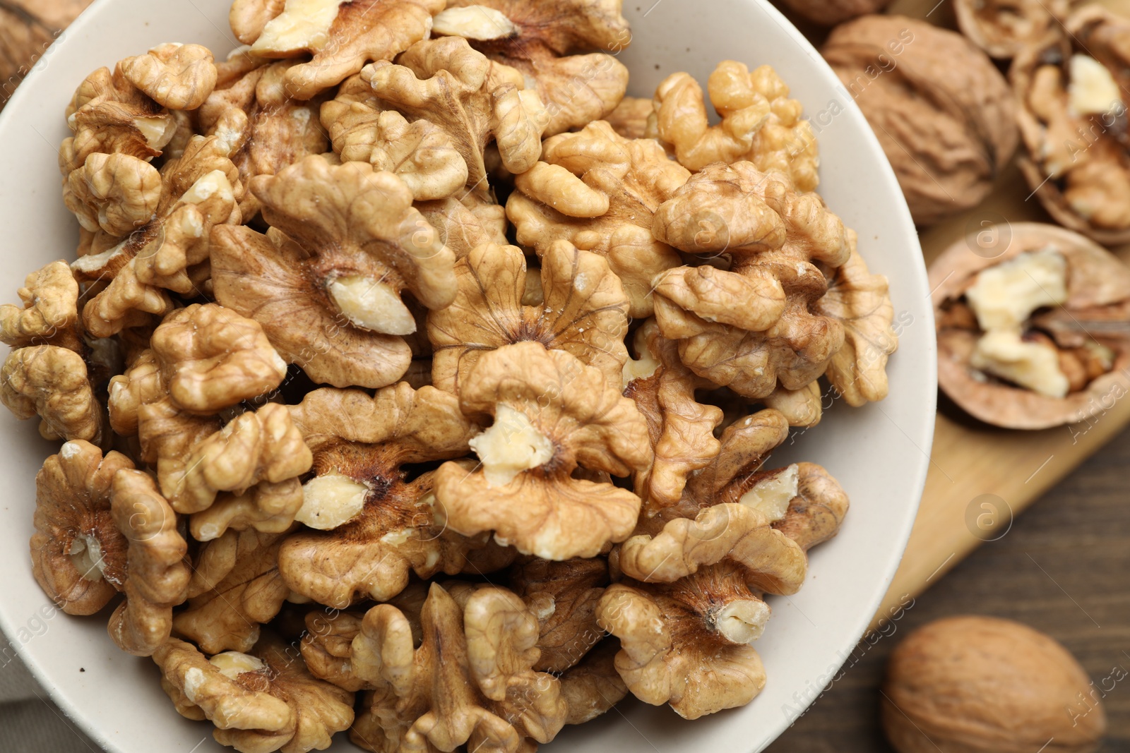 Photo of Peeled walnuts in bowl on table, top view