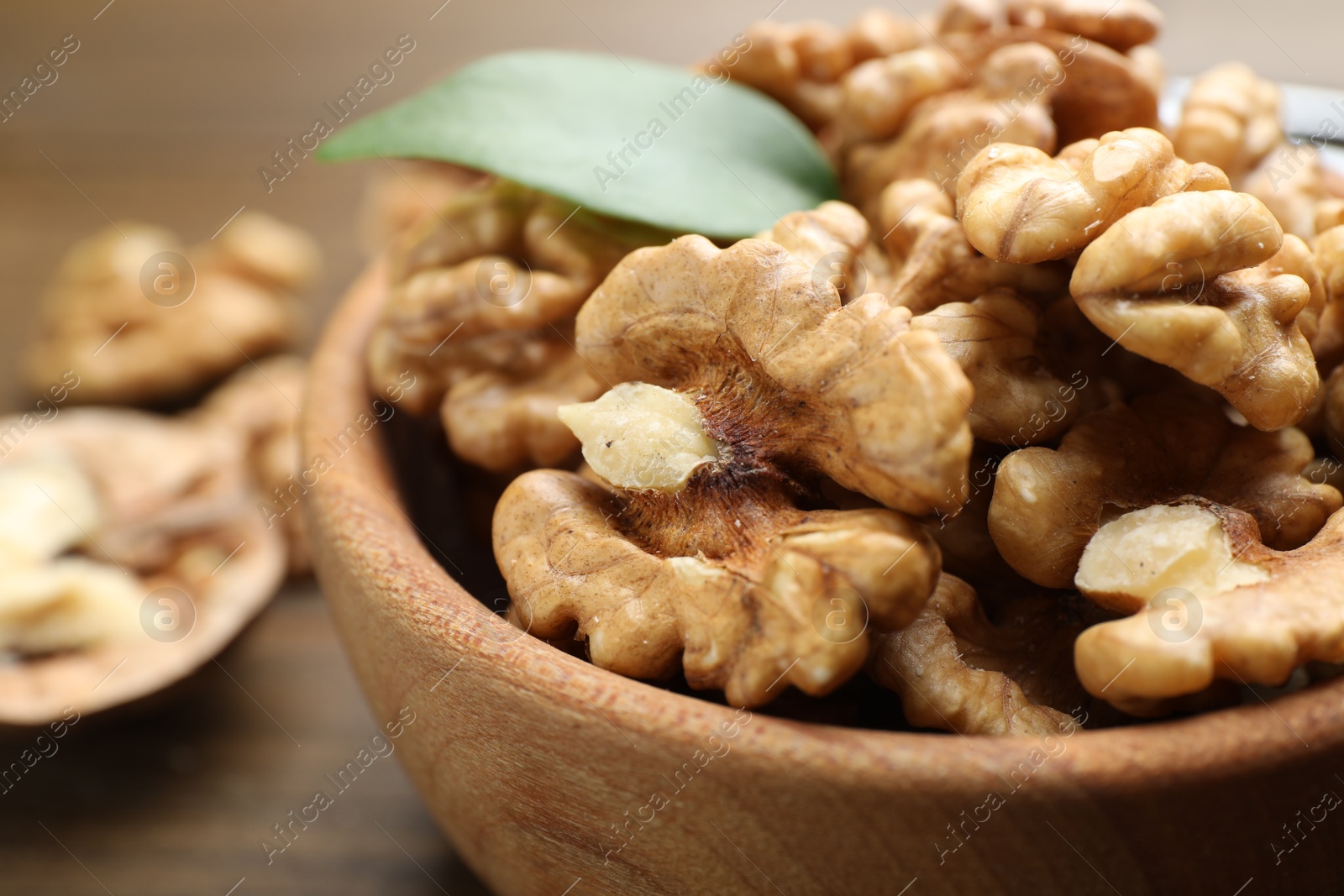 Photo of Peeled walnuts in bowl on table, closeup