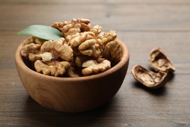 Photo of Peeled walnuts in bowl on wooden table, closeup