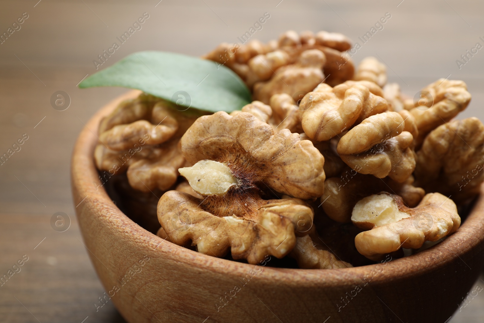 Photo of Peeled walnuts in bowl on table, closeup