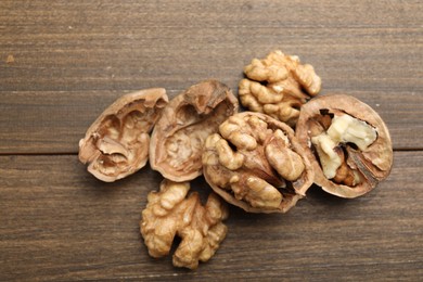 Photo of Fresh walnuts with shells on wooden table, flat lay