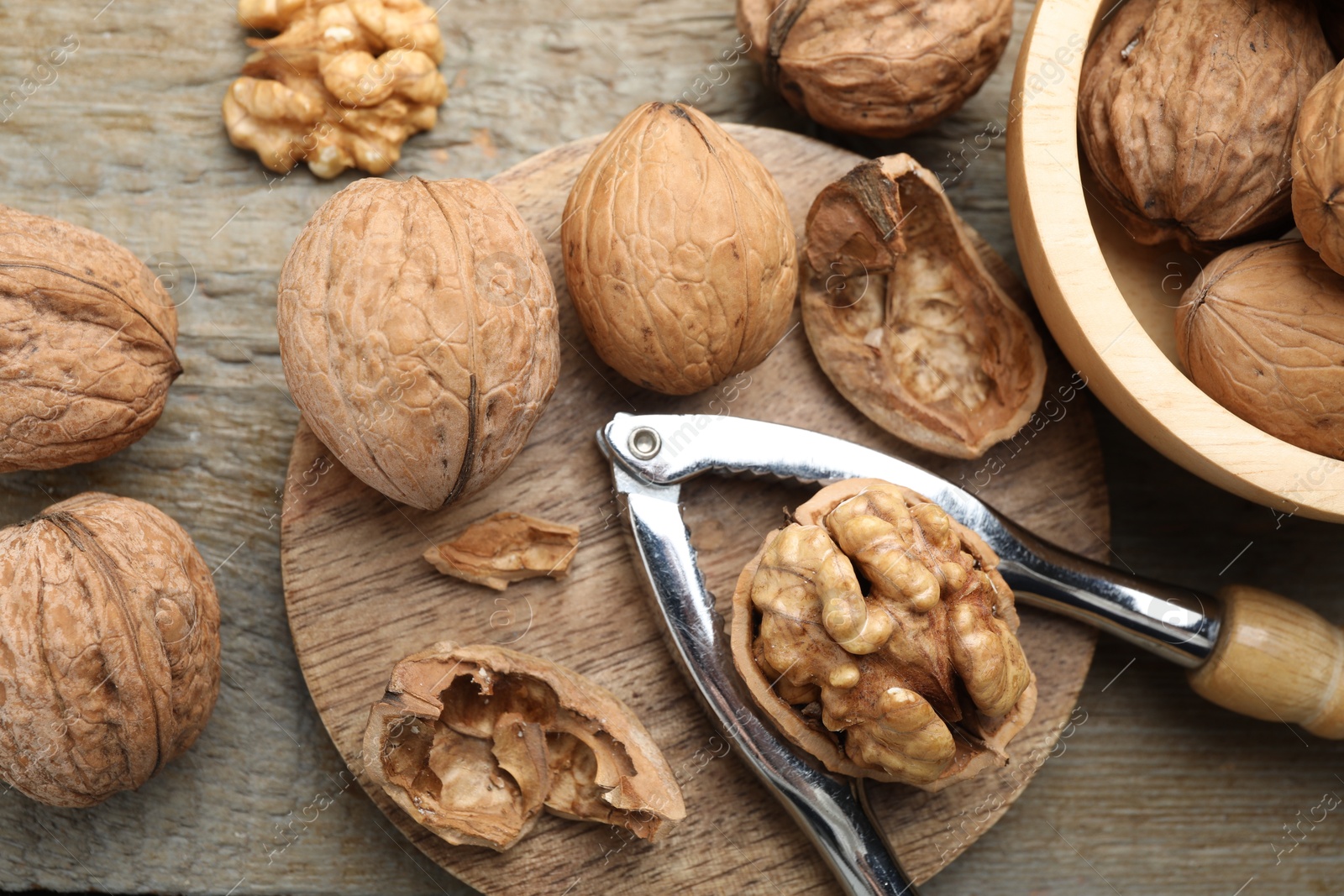 Photo of Fresh walnuts and nutcracker on wooden table, flat lay