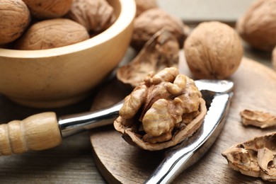 Photo of Fresh walnuts and nutcracker on table, closeup