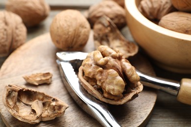 Photo of Fresh walnuts and nutcracker on table, closeup