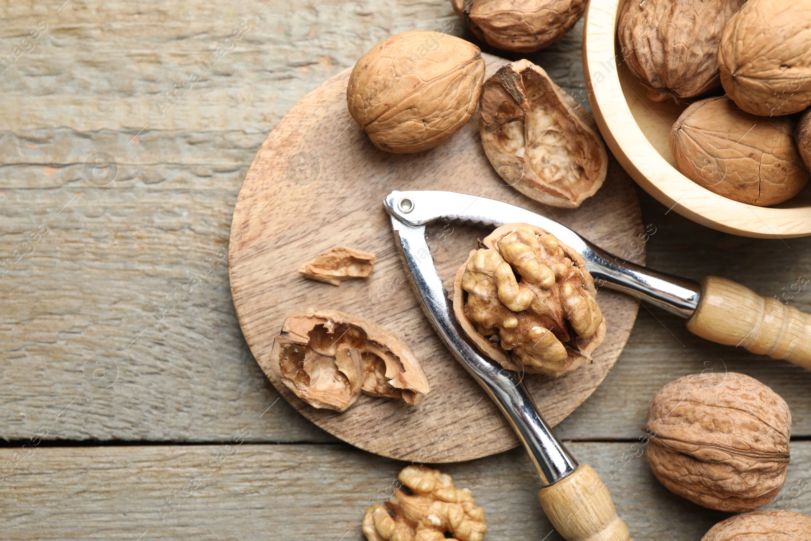 Photo of Fresh walnuts and nutcracker on wooden table, flat lay. Space for text