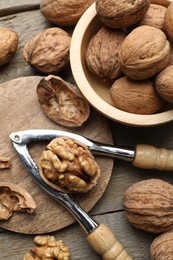 Photo of Fresh walnuts and nutcracker on wooden table, flat lay