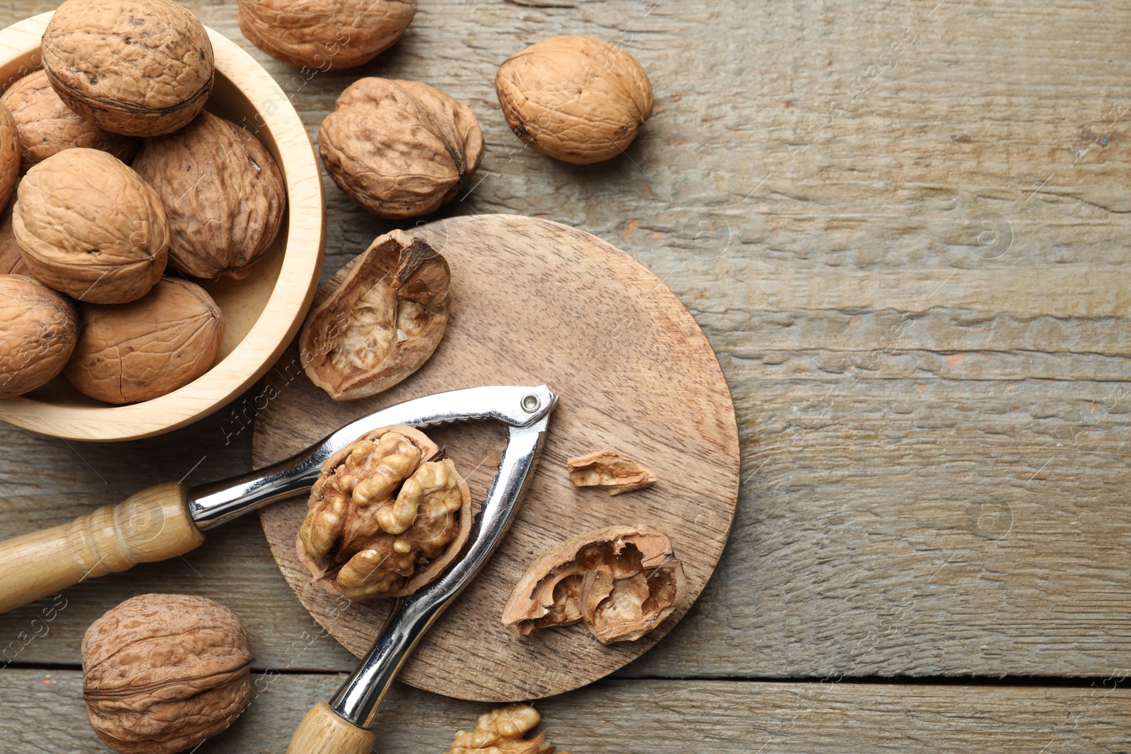 Photo of Fresh walnuts and nutcracker on wooden table, flat lay. Space for text