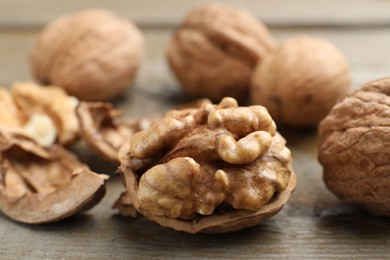 Photo of Fresh walnuts with shells on wooden table, closeup