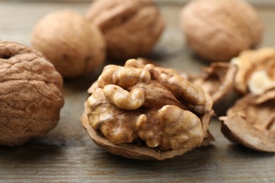 Photo of Fresh walnuts with shells on wooden table, closeup