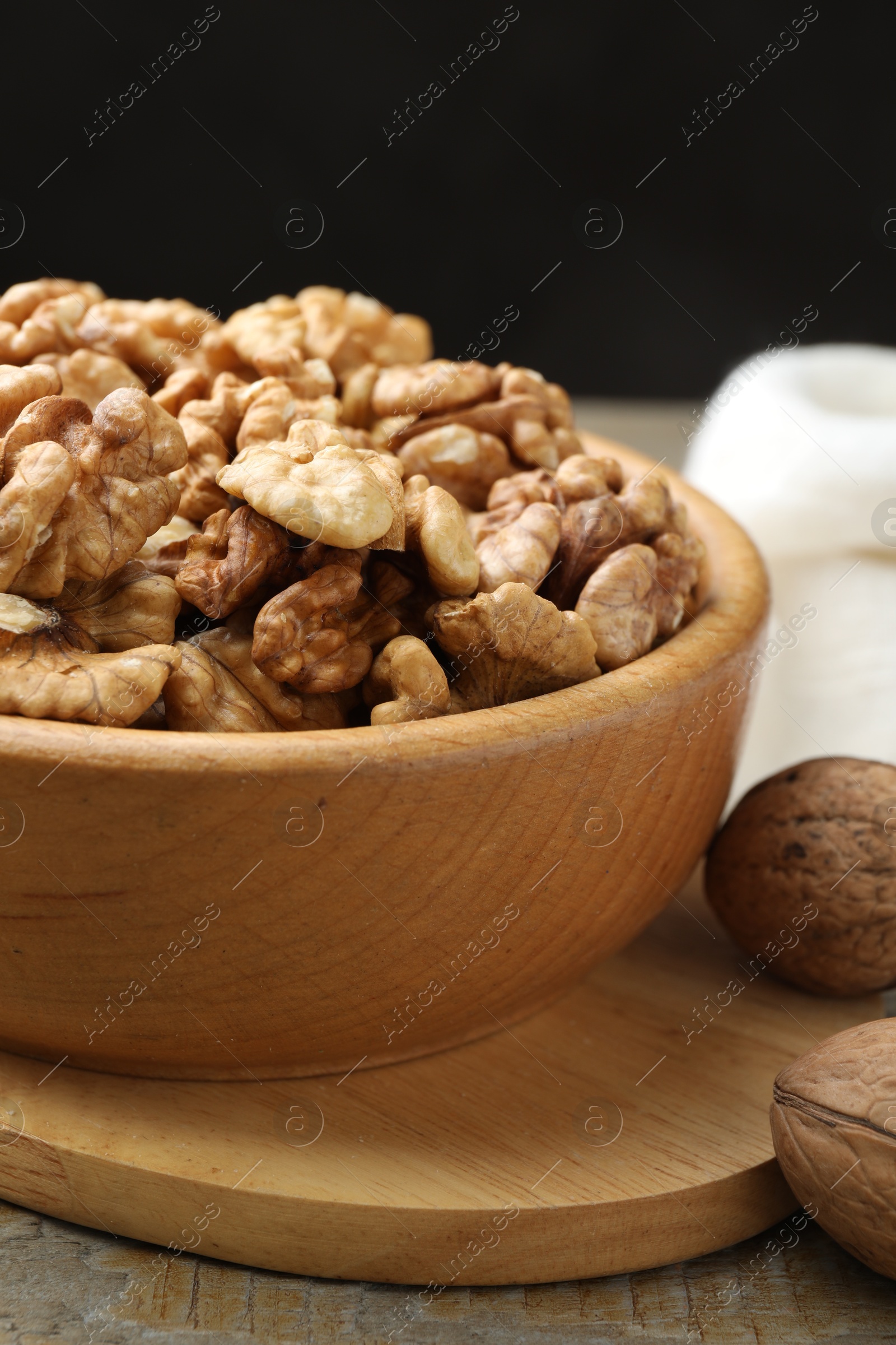 Photo of Peeled walnuts in bowl on wooden table, closeup