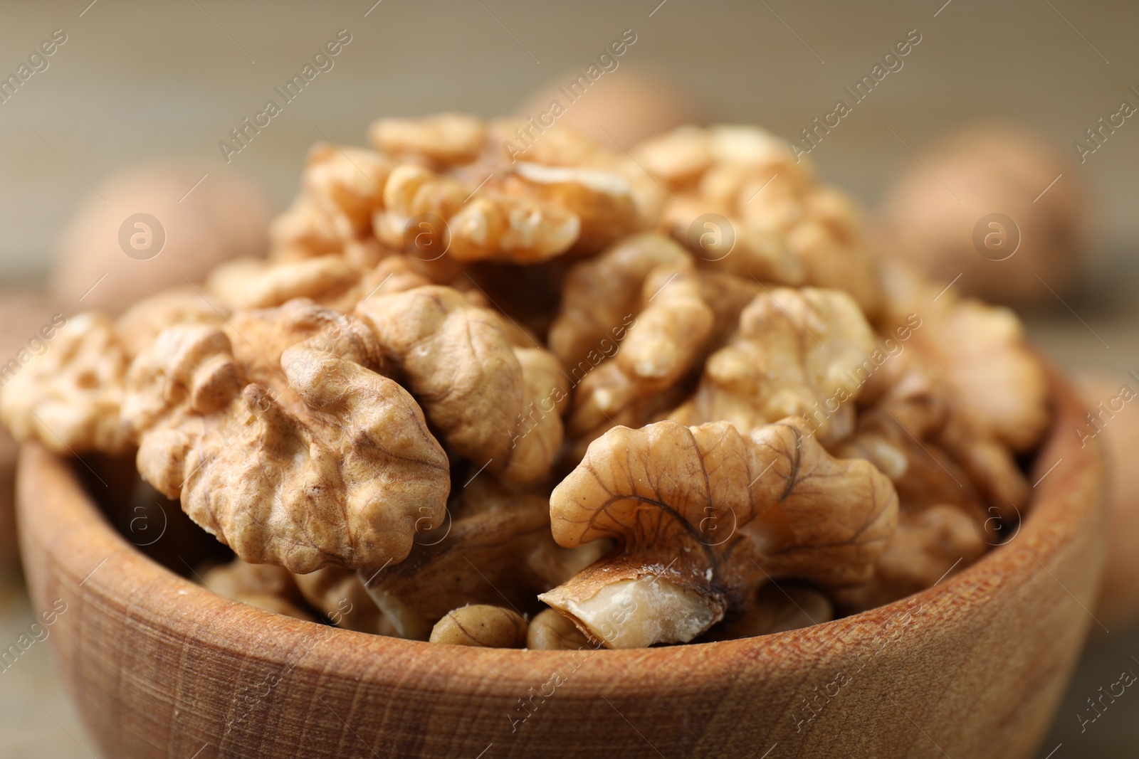 Photo of Peeled walnuts in bowl on table, closeup