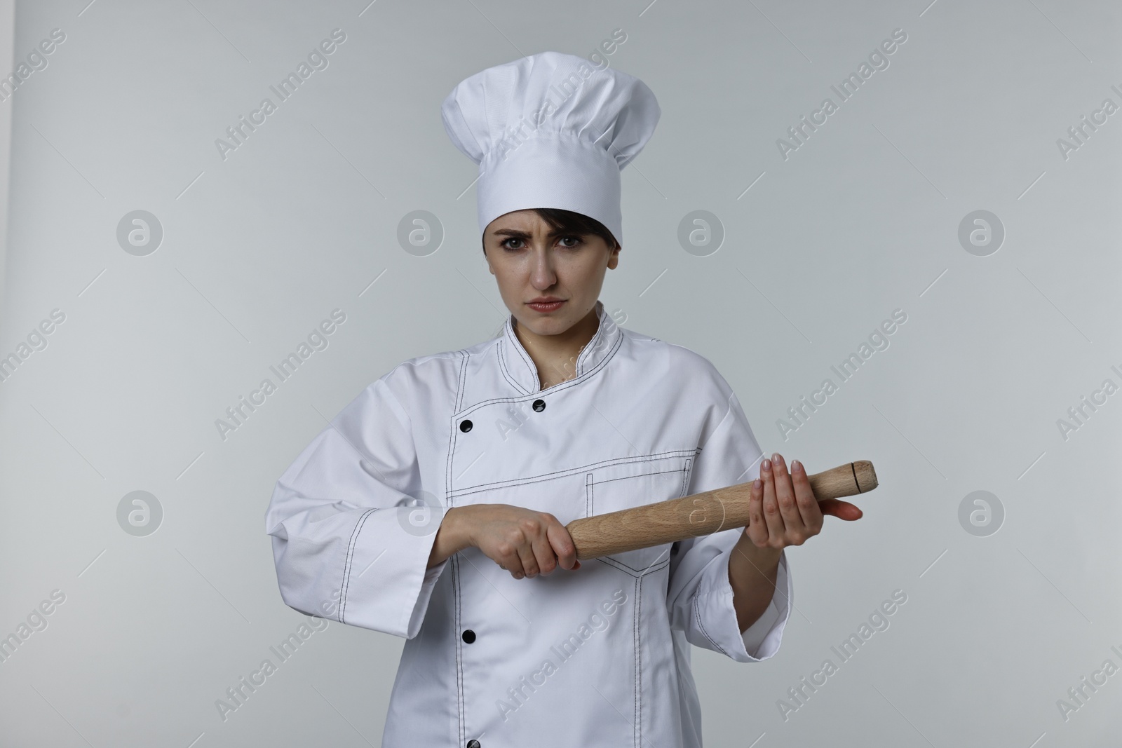 Photo of Professional chef with rolling pin on light grey background