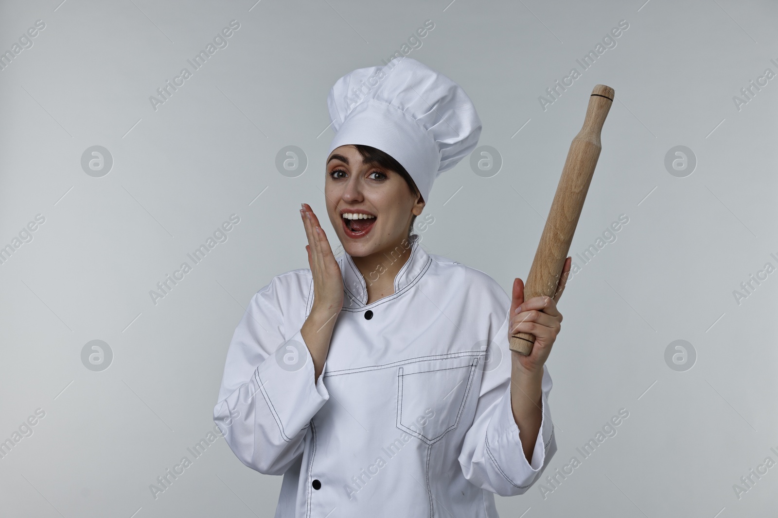 Photo of Emotional chef with rolling pin on light grey background