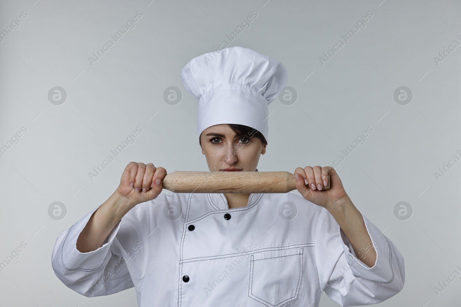 Photo of Professional chef with rolling pin on light grey background