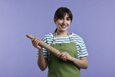 Photo of Happy woman with rolling pin on violet background