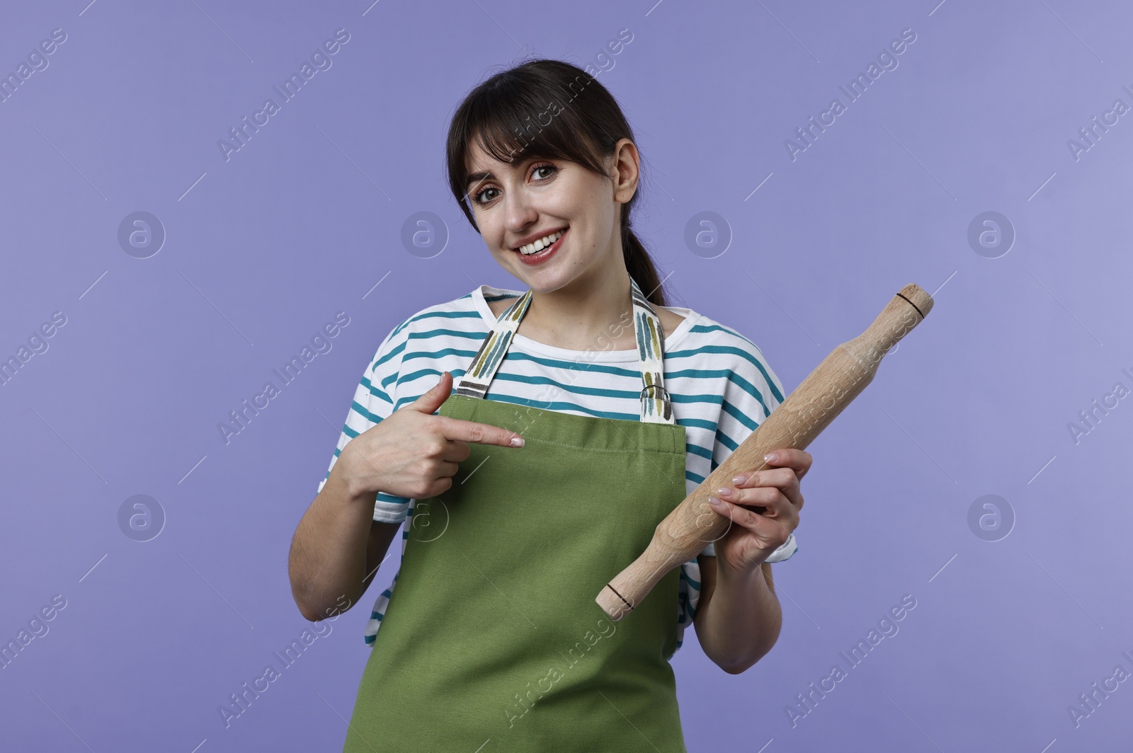 Photo of Woman pointing at rolling pin on violet background