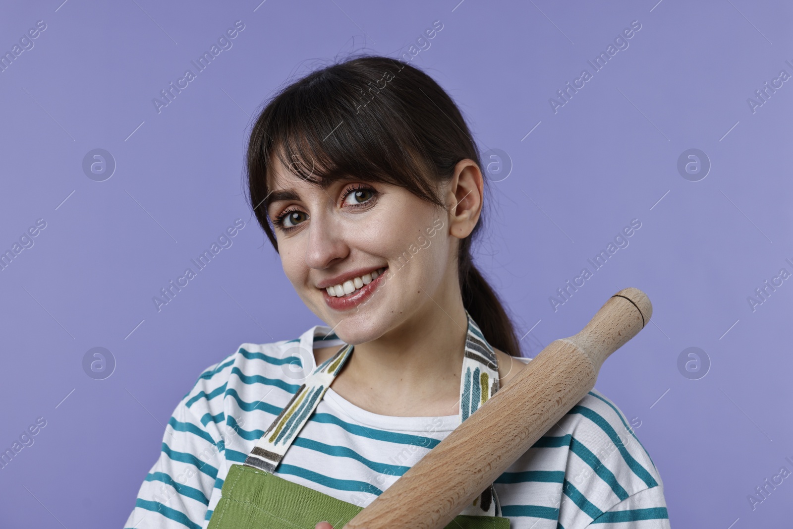 Photo of Happy woman with rolling pin on violet background