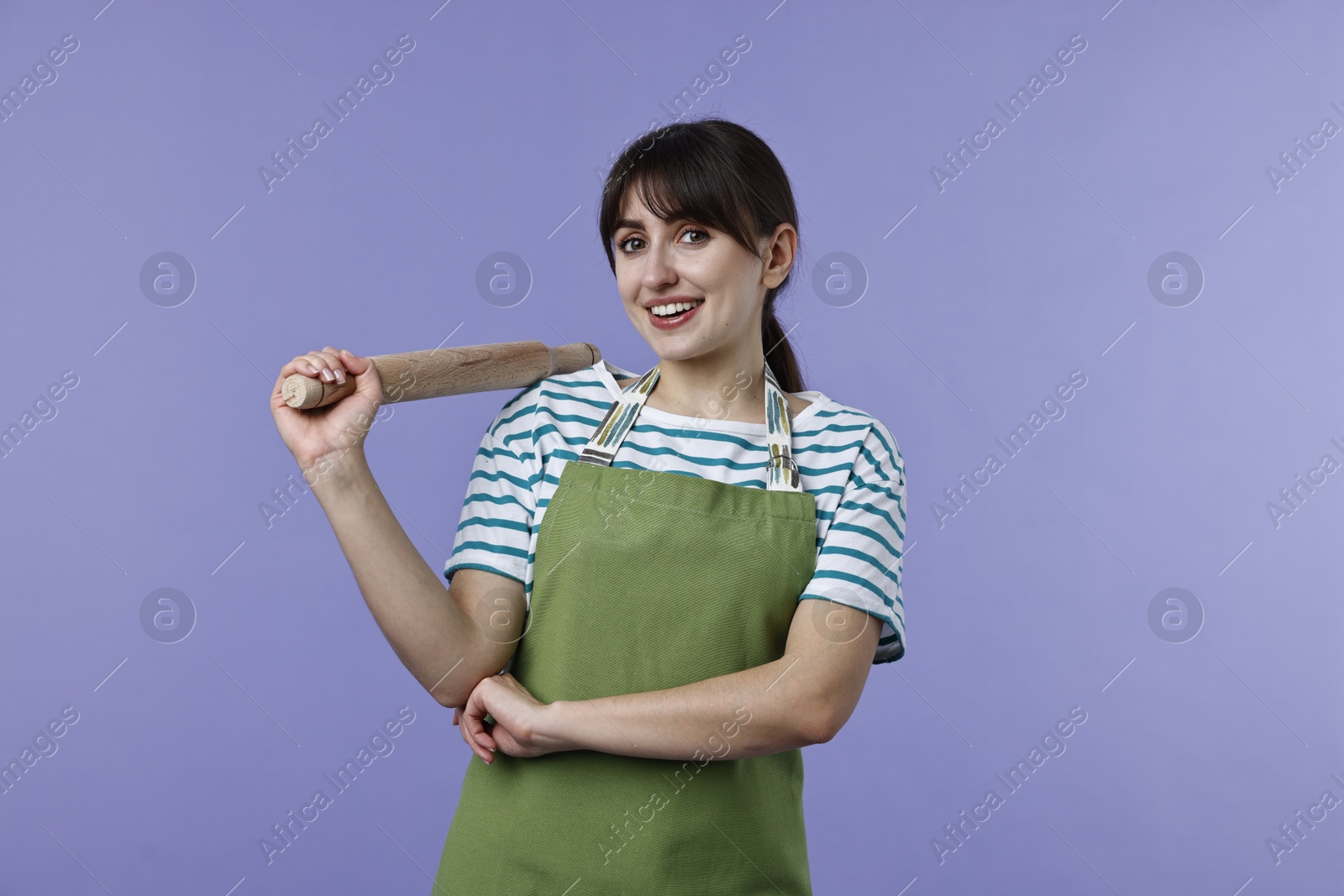 Photo of Happy woman with rolling pin on violet background