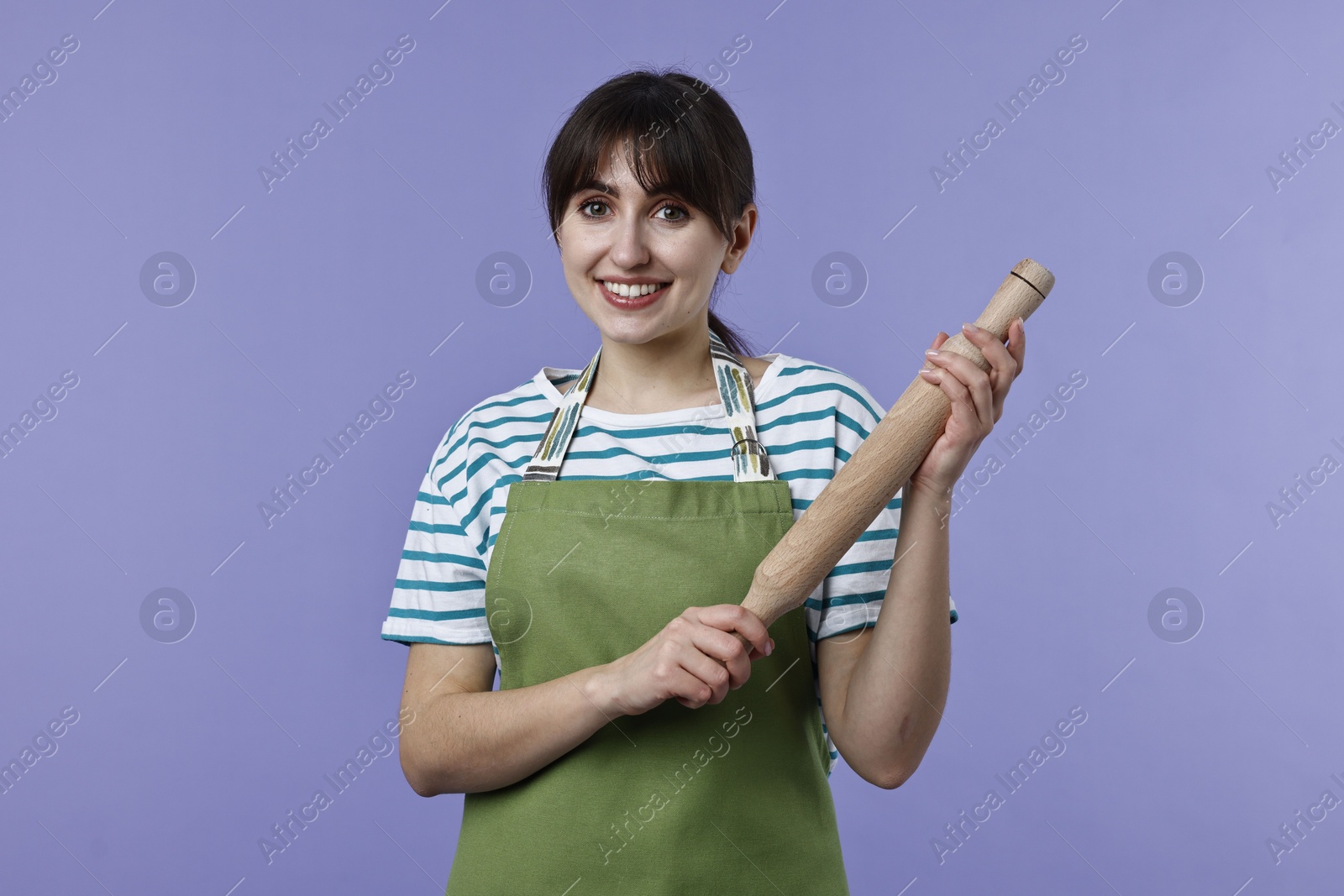 Photo of Happy woman with rolling pin on violet background