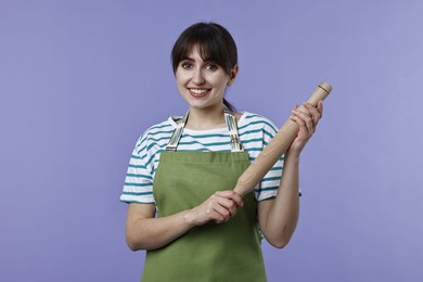 Photo of Happy woman with rolling pin on violet background